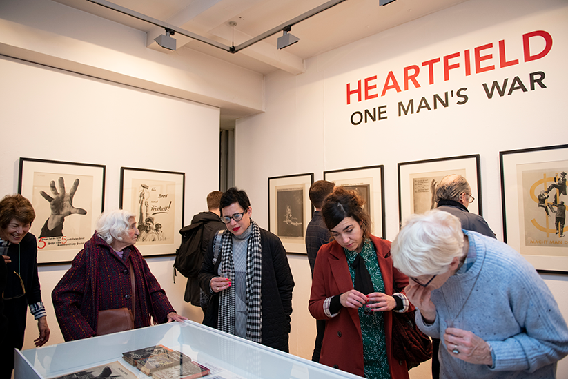 Five people standing in a gallery, looking into a glass display case. 