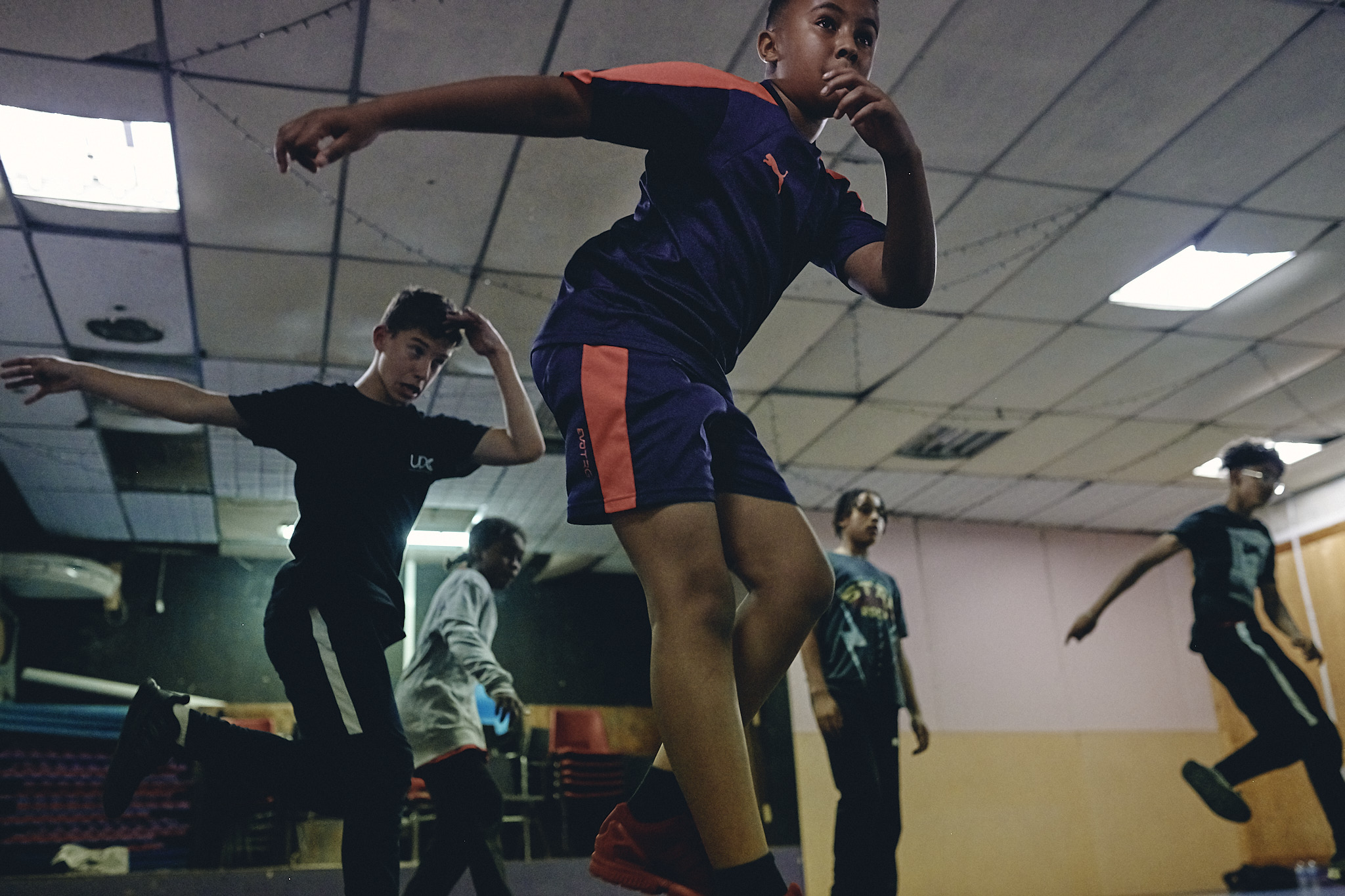 A group of boys performing a choreographed dance in a hall. 