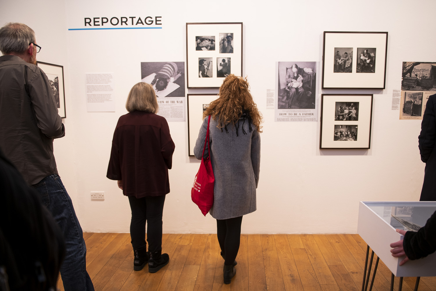 People seen from behind, looking at framed photographs on the gallery wall 