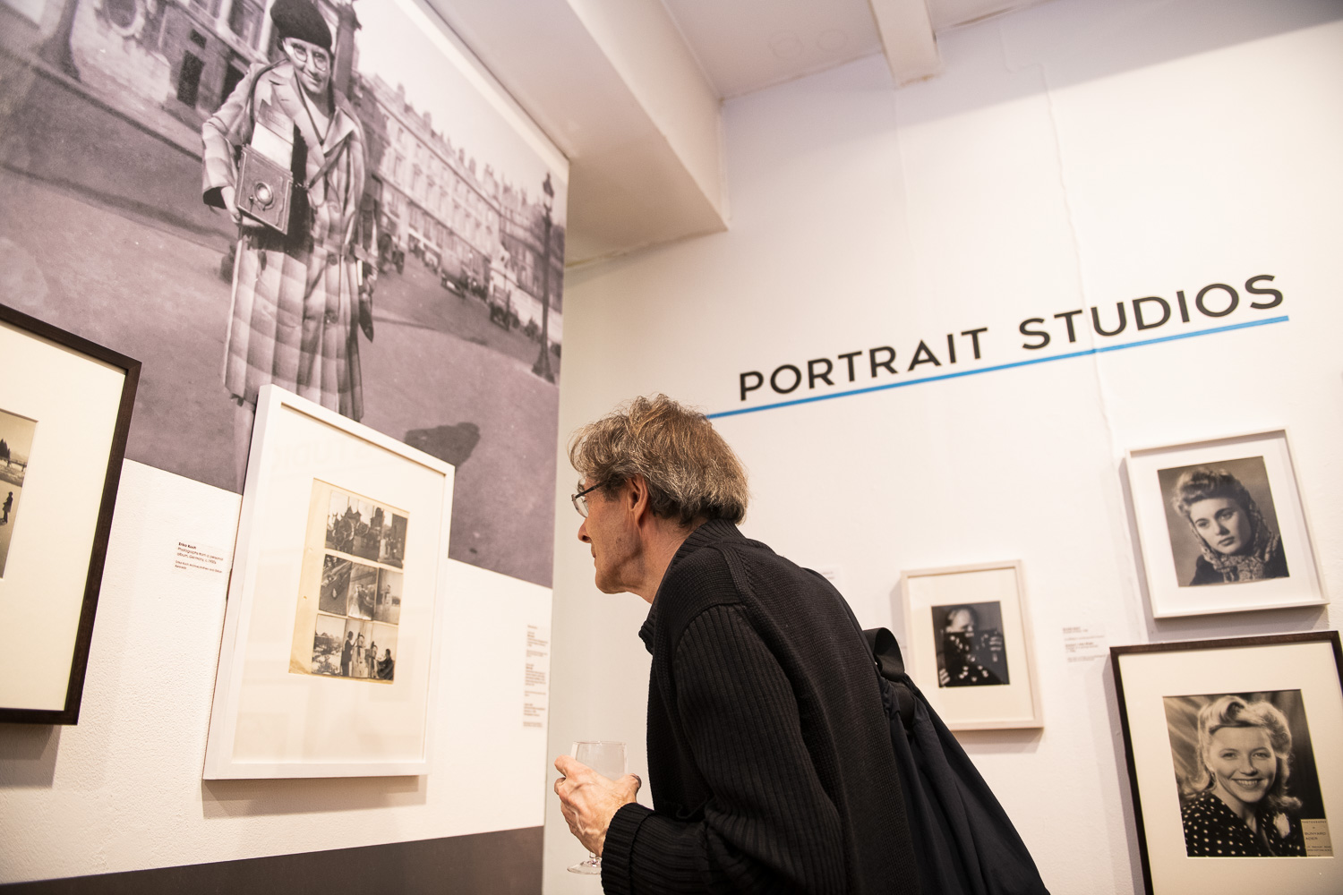 A person leans in to get a closer look at a photograph hanging on the gallery wall