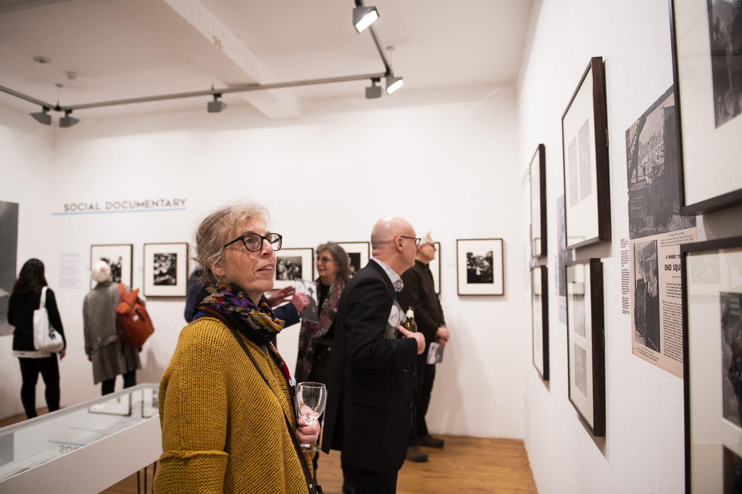 A busy gallery. People are looking at framed photographs on the gallery walls. 