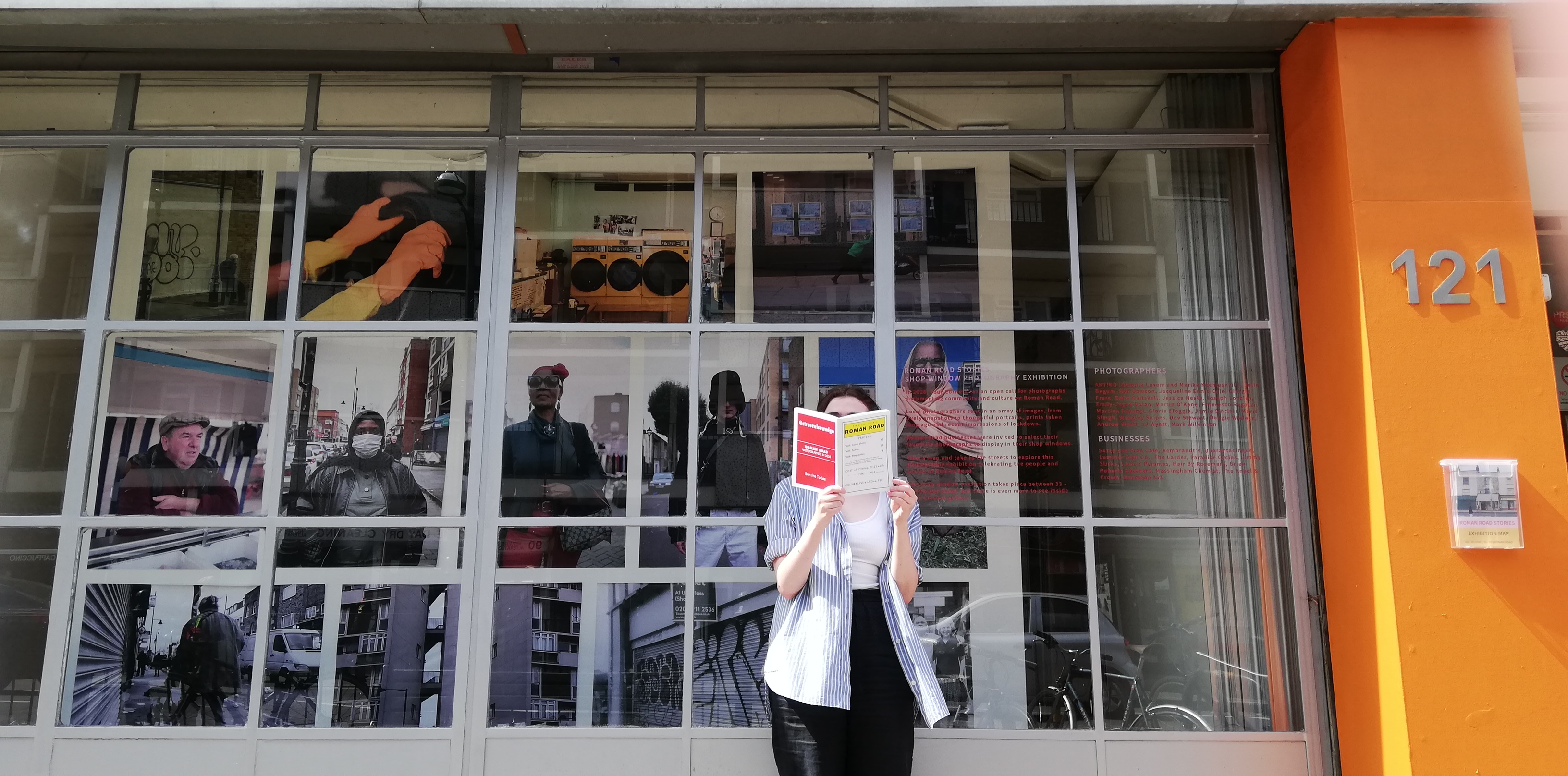 A woman stands in front of Four Corners gallery window, reading a zine