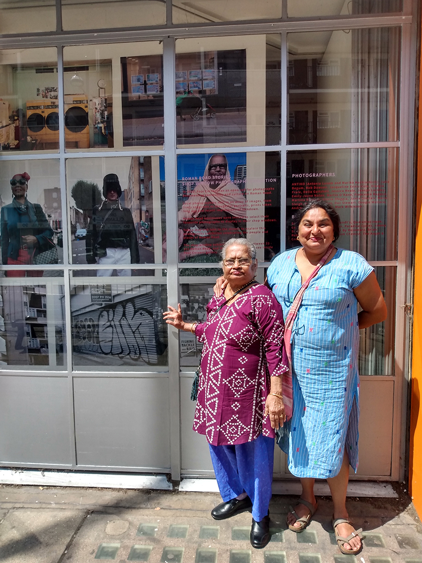 A mother and her adult daughter stand in front of Four Corners' gallery window, which is filled with large portrait photographs