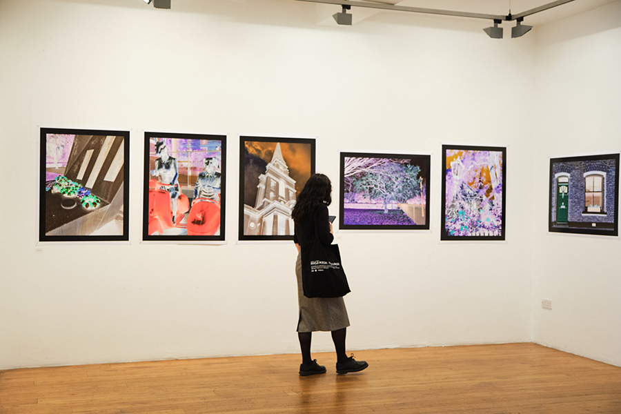 White-walled gallery with a person looking at brightly-coloured art on the walls.