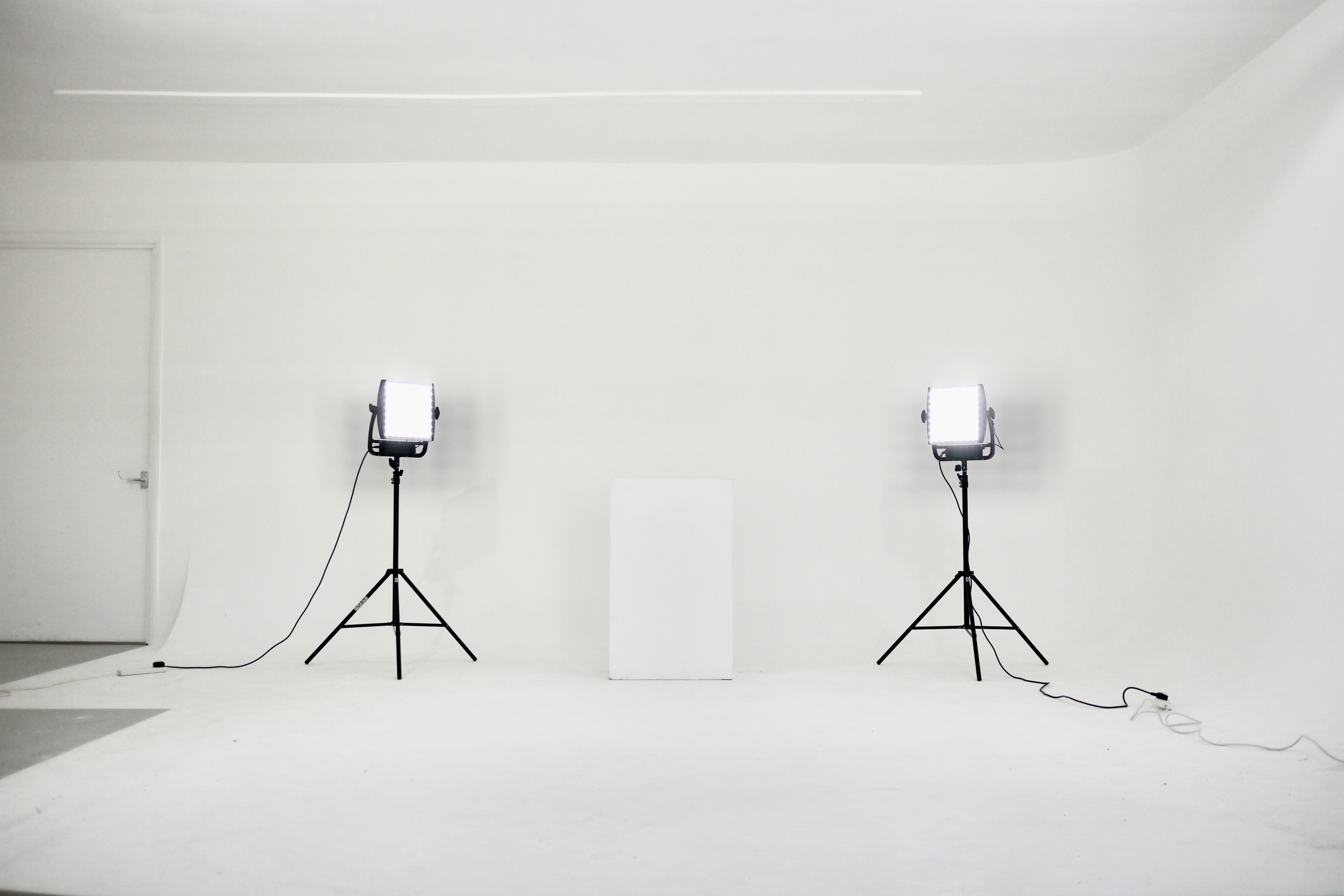 White infinity studio with two large black box lights, a black chair, and some wires and boxes.
